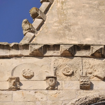 Padria, chiesa parrocchiale di Santa Giulia. Cornice orizzontale a rosette, sferule, punte di diamante e volti umani della facciata. (foto Ivo Piras)